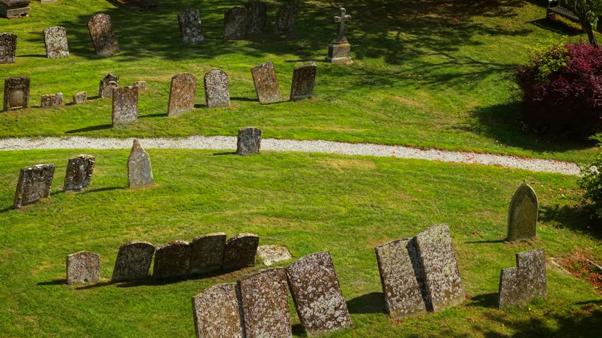 Graveyard headstones around green cemetery lawn. Old graves and burial markers near curved white path and stone cross. Halloween cemetery with ghost, mystic and ancient burial concept