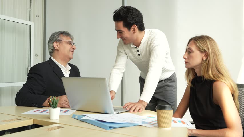 A group of male business professionals is presenting to a male executive and a female secretary during a meeting in a corporate conference room.
