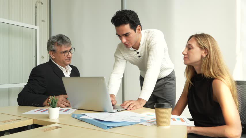A group of male business professionals is presenting to a male executive and a female secretary during a meeting in a corporate conference room.
