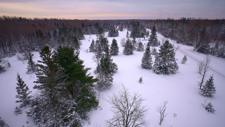 Aerial view of a road cutting through a snow-covered landscape in Northern Michigan