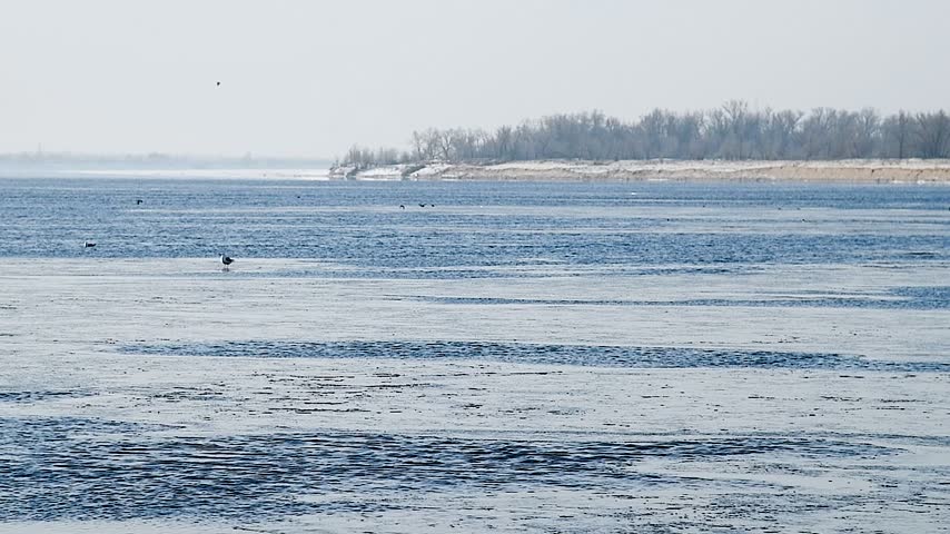 Snow river winter landscape. Frozen ice and snow by river. Spring thawed ice on water.