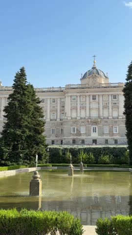 The monumental Royal Palace of Madrid, also known as the Palacio Real, is beautifully reflected in the pool of the Sabatini Gardens fountain on a sunny day in the capital city of Spain
