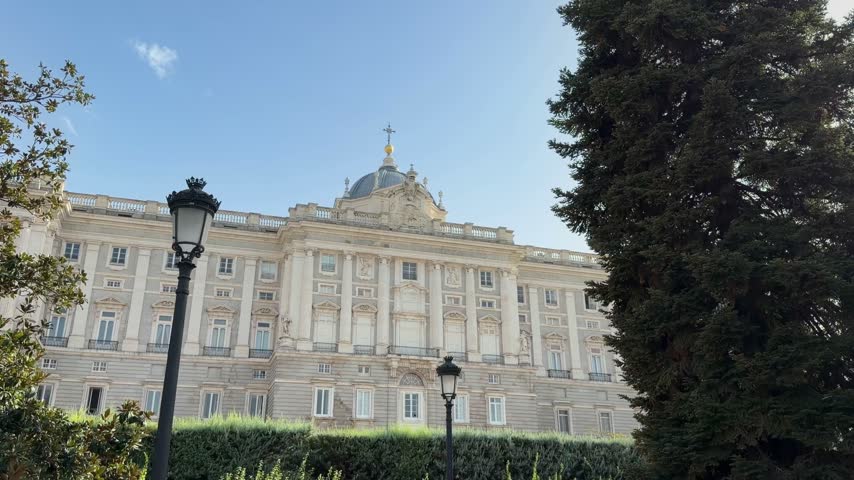 Sunny day view of the majestic facade of the Royal Palace of Madrid, also known as Palacio Real, from the beautiful and lush Sabatini Gardens, a famous landmark and touristic destination