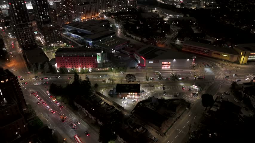 Aerial view busy London road intersection at night with illuminated streets, traffic and high-rise buildings