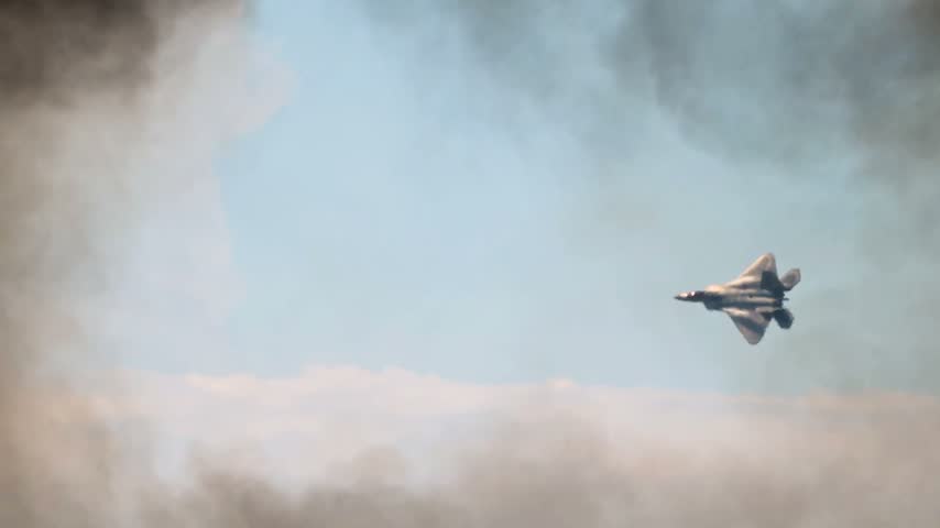 US Air Force F-22 Raptor Stealth Fighter Jet Soaring Through Dense Smoke and Clouds During Aerial Demonstration Flight.
