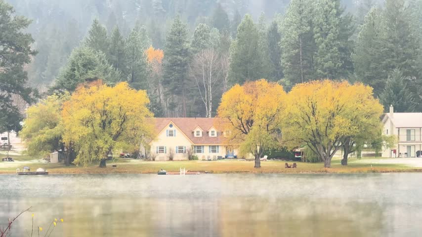 Static shot of a house beside Round Lake near Princeton, British Columbia, under soft overcast light with calm reflections on the water.