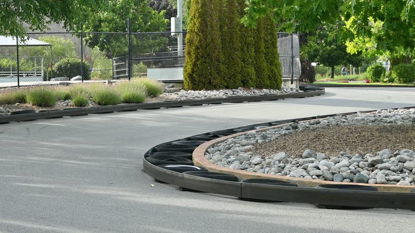 Static shot of an outdoor go kart track edged with tires and a chain link fence amid greenery in Penticton, British Columbia.