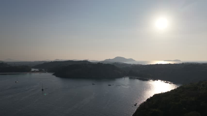 Scenic drone footage of a boat-filled bay nestled between two rocky headlands.
