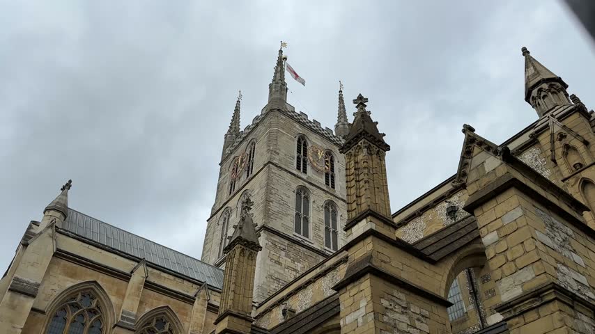 Upward view of an ornate Gothic church facade and tower in central London.