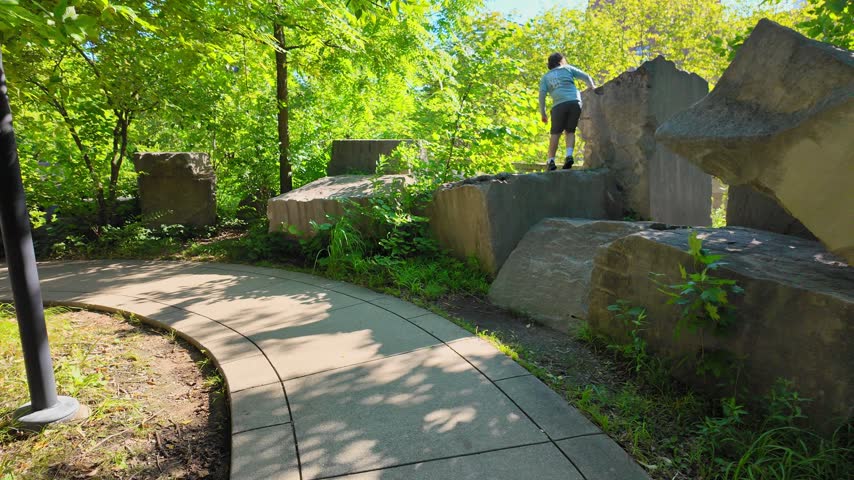 Young boy climbing on large stones in the Watanabe Garden in Indianapolis, Indiana, USA