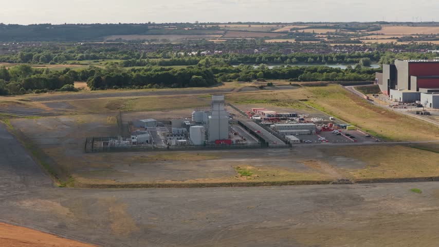 Large industrial Energy from Waste power plant facility generates electricity during the daytime with surrounding green fields and open rural land visible from an elevated perspective in England