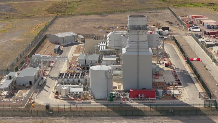 An industrial facility turns waste into energy, using large tanks and chimneys in a rural landscape to power the local community and surrounding regions.