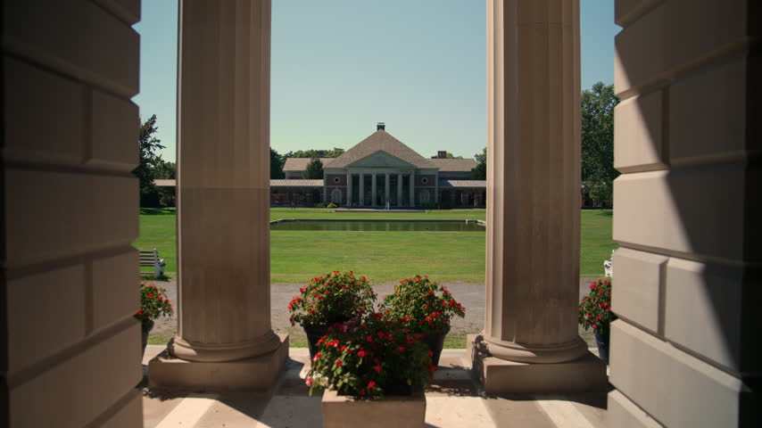 View through the towering columns of the Hall of Springs in Saratoga Springs, New York, framing the historic Roosevelt Bathhouse across the reflecting pool.