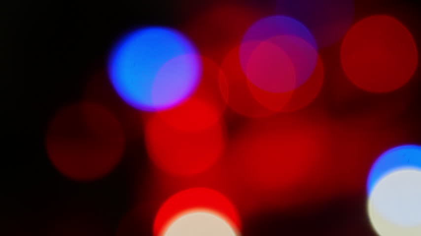Police car with flashing red and blue emergency lights parked at night accident scene. Service vehicle in bokeh blur. Police law enforcement vehicle lights flashing glow red and blue in crime scene.