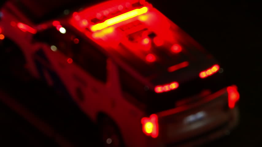Police car with flashing red and blue emergency lights parked at night accident scene. Service vehicle in bokeh blur. Police law enforcement vehicle lights flashing glow red and blue in crime scene.