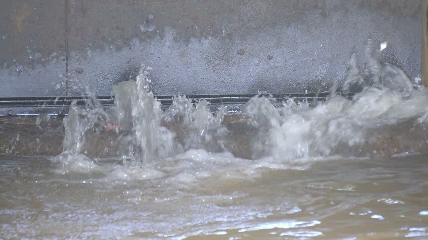 High Pressure Water Flowing Out of Dam Outlet Gate in Hydroelectric Canal. Water Gushing Through Sluice Gate Spillway in Reservoir.