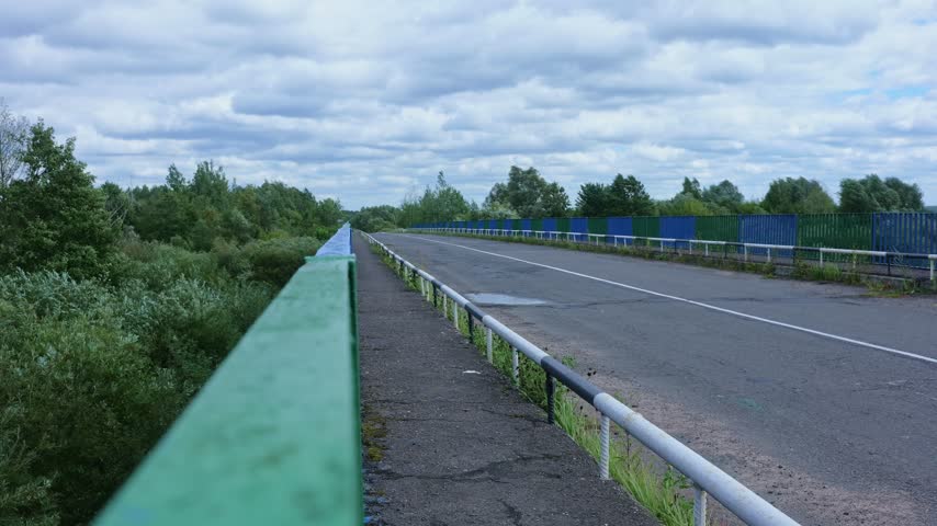 Highway bridge with turquoise railings stretching toward forest, Byten Belarus