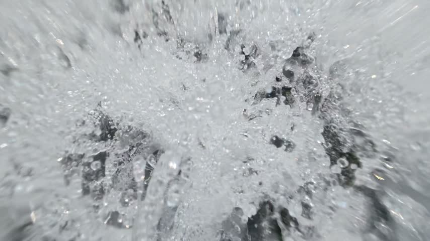 Close up of turbulent rushing water with white foam and splashing bubbles
