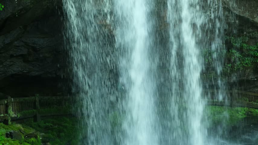 a walking path and moss-covered fence behind the waterfall