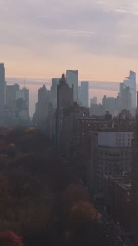Vertical video: Journal Square skyscrapers construction city in Jersey City, New Jersey, aerial view in a foggy autumn day, featuring traffic flowing on highway at dusk