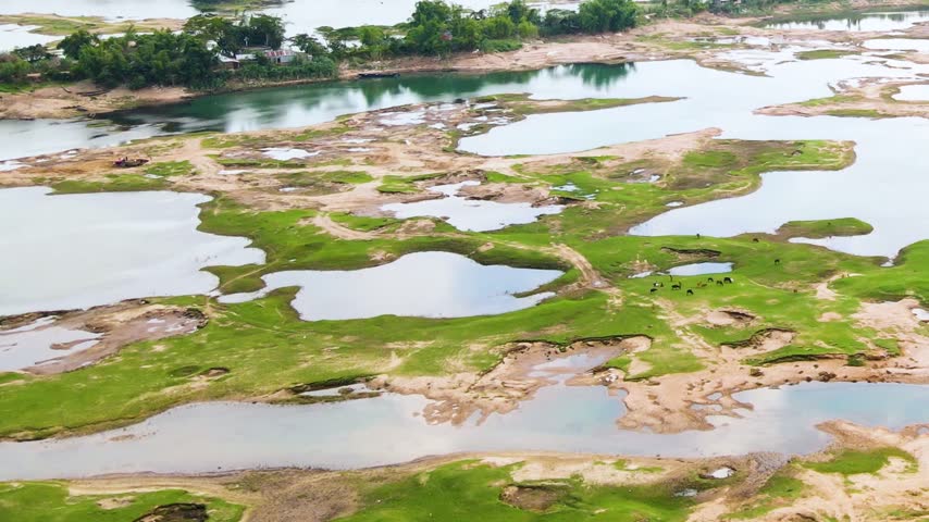 Small braided river dried up and exposed riverbed in winter season at rural village - aerial tilt down.