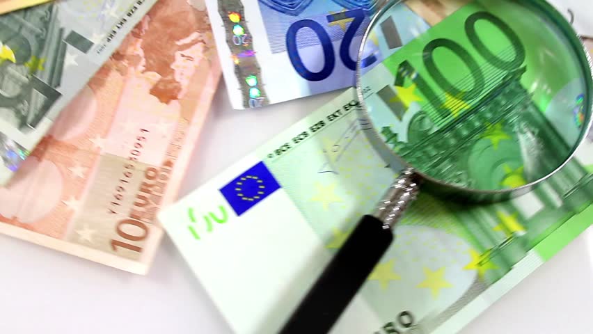 Magnifying glass over spinning Euros. Euro paper notes passing in front of