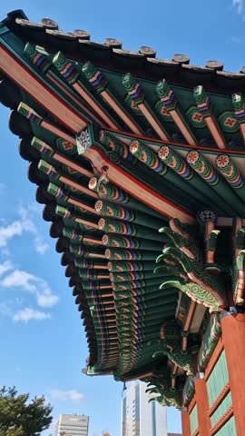Vertical View of Traditional Korean Dancheong Paintings on Curved Eaves at Temple