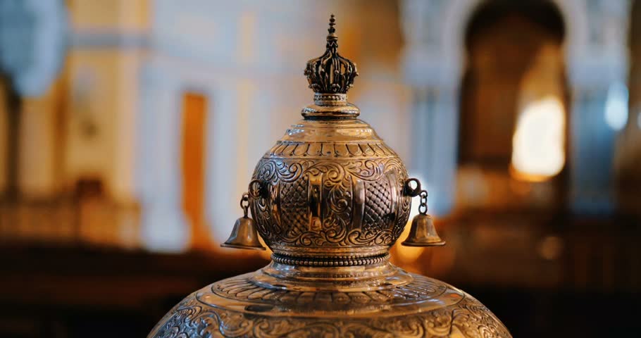 Ornate silver Torah scroll finial ornament inside a synagogue, traditional Judaica artifact for Yom Kippur Day of Atonement and High Holy Days.
