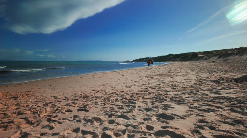 Panoramic shot of Bolonia beach in Tarifa, Spain, with horse rider galloping away