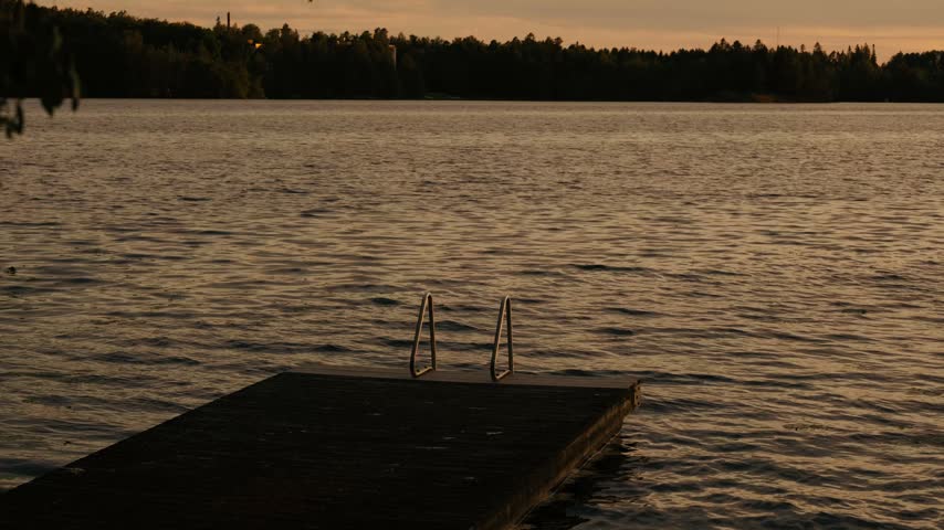 Calm evening lake scene with a wooden dock reaching into gentle water, warm sunset lighting, silhouetted forest shoreline, and peaceful golden reflections.