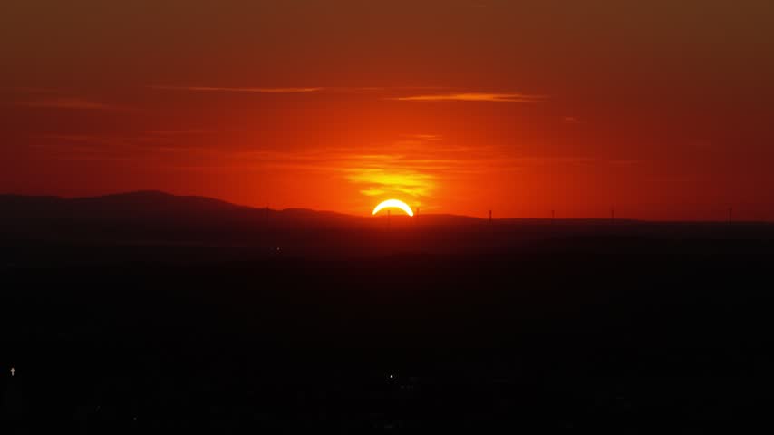 Dramatic partial solar eclipse during sunset with a beautiful red and orange glowing sky