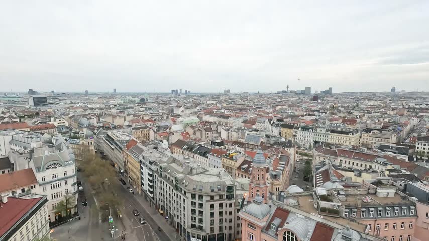 Panoramic aerial view of Vienna, Austria, featuring historic rooftops, streets, dense urban buildings and the distant skyline.