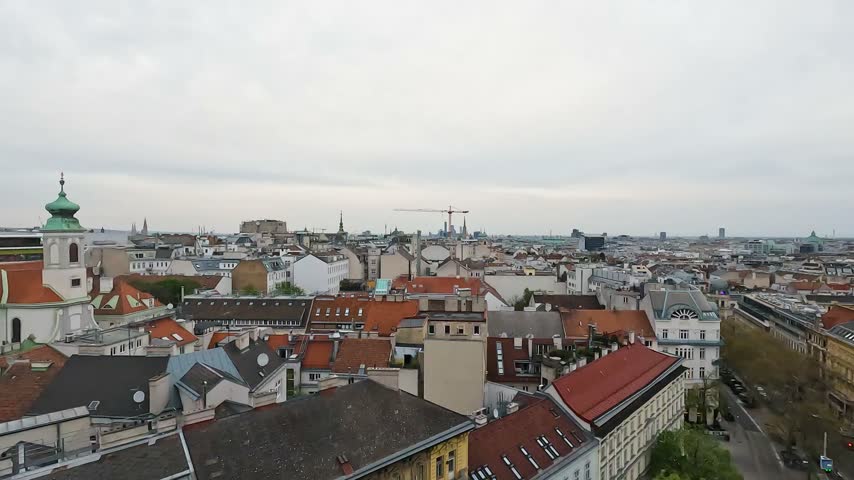 Aerial view across central Vienna, Austria, showing historic rooftops, dense urban buildings, streets and the city skyline.