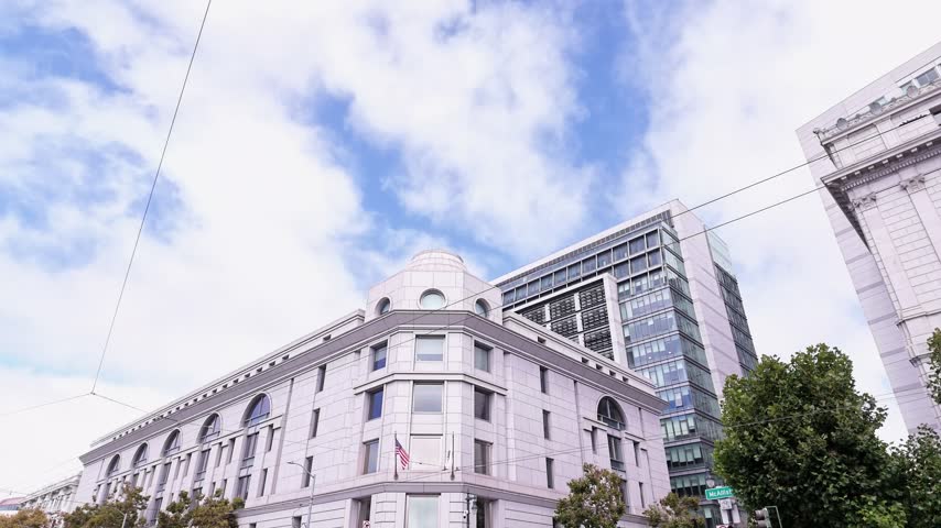 Low angle view of the Phillip Burton Federal Building and United States Courthouse in downtown San Francisco, California, with clouds moving across the blue sky on a bright day