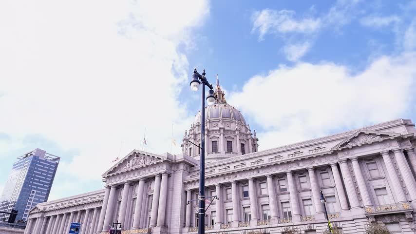 Historic San Francisco City Hall showcasing its impressive Beaux-Arts architecture with a grand dome and ornate facade under a partly cloudy sky, a landmark of American government and justice