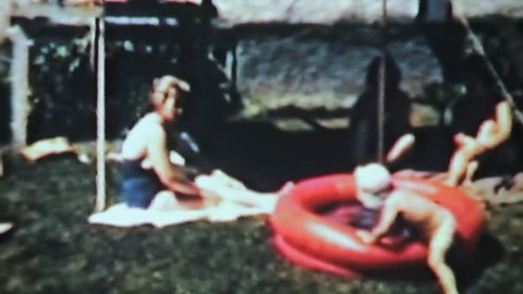 A cute little boy enjoys splashing around in a kiddie pool while his mom, aunt and grandmother look on in 1963.