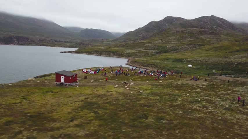 Aerial view orbiting a distant tent camp in Greenland, cloudy day in the arctic