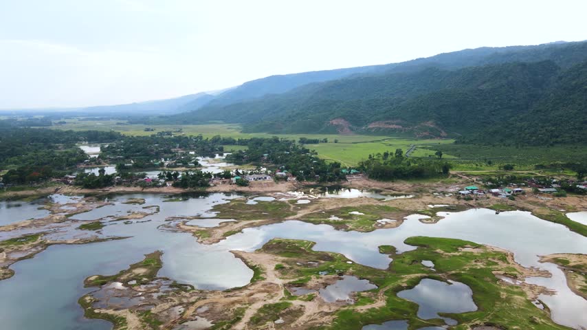 Stunning aerial footage of a mountain valley with a village nestled along a partially dry riverbed