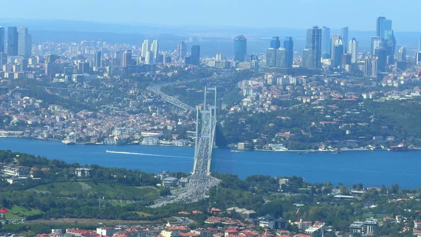 Aerial perspective of Istanbul showcasing the Bosphorus Bridge, urban skyline, and green areas along the water