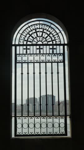 Cityscape of Gijon, Spain, seen through an old wrought iron church window with religious crosses