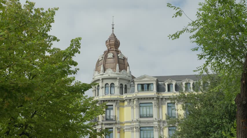Historic bank building with a domed corner tower framed by lush trees