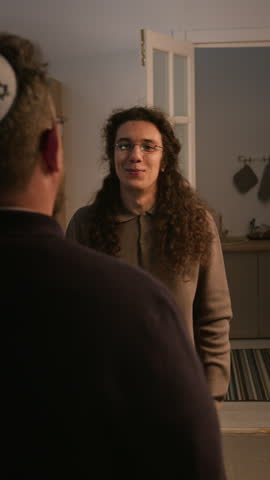 Vertical video of Jewish Caucasian men hugging and greeting each other during Hanukkah holiday meeting at home. Suitable for family reunion ads and religious diversity video projects