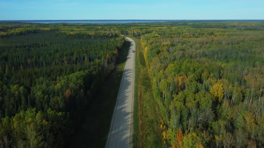 Highway in Northern Alberta during fall with trucks traveling along the roadway