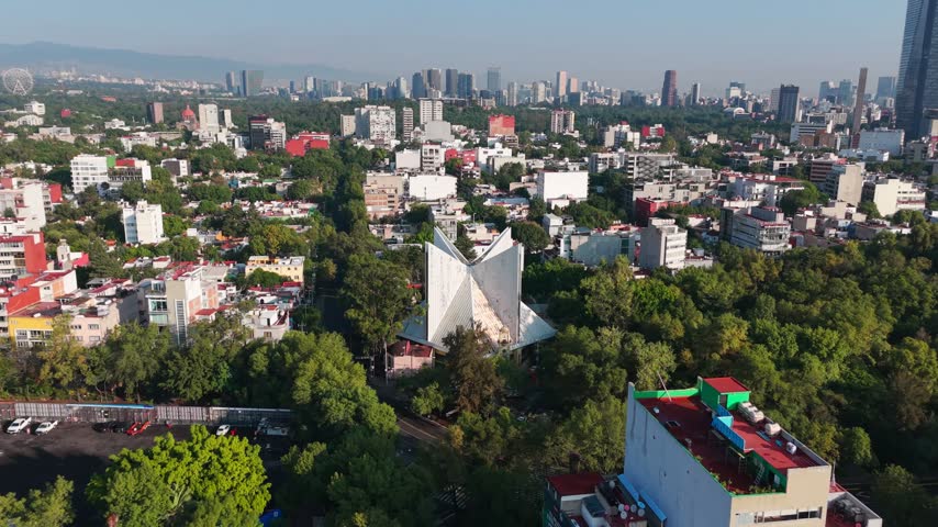 Aerial view of the Parroquia de la Medalla Milagrosa surrounded by lush trees and urban buildings in the La Condesa neighborhood of Mexico City, Mexico.