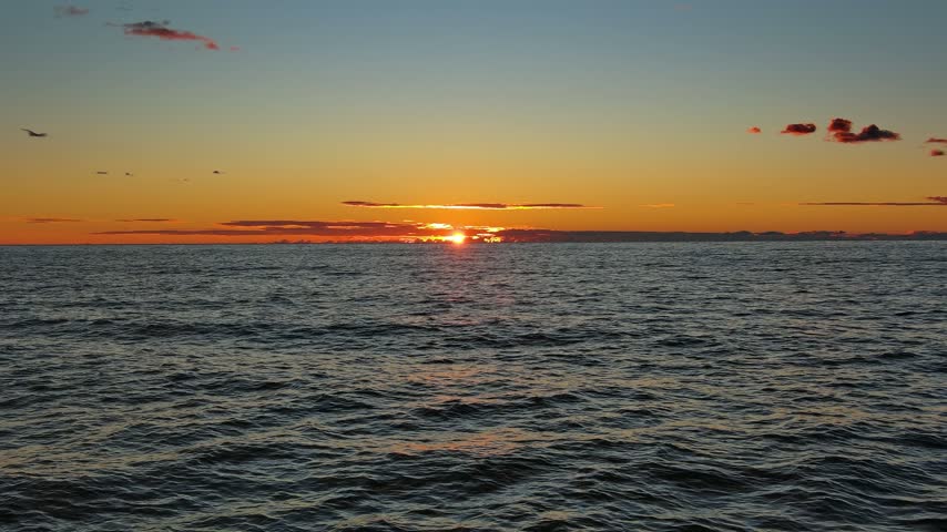 Aerial view of sunset over the calm Adriatic Sea with a vibrant orange and yellow sky, Montenegro.