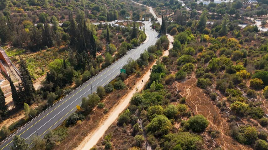 Aerial view of the winding road through the lush greenery and trees of Ein Karem National Park in Jerusalem, Jerusalem District, Israel.
