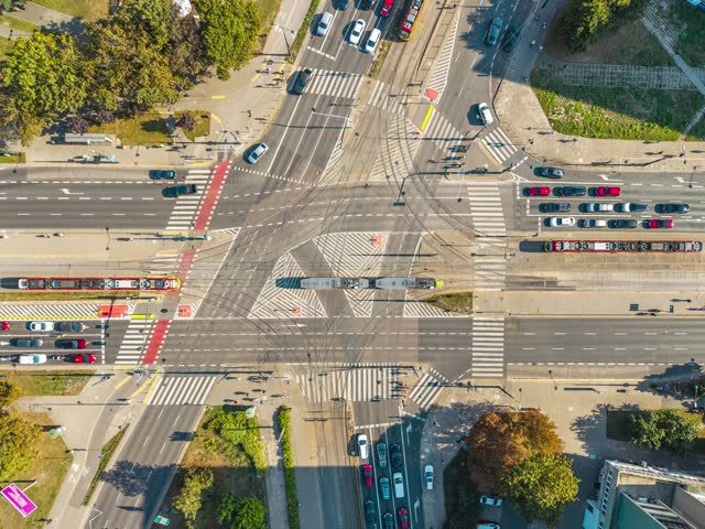 Aerial view of a complex urban intersection featuring tram tracks, crosswalks, and traffic in Poland.