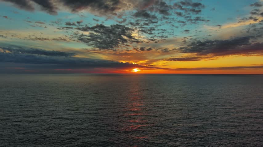 Aerial view of a vibrant sunset over the calm waters of the Adriatic Sea in Montenegro.