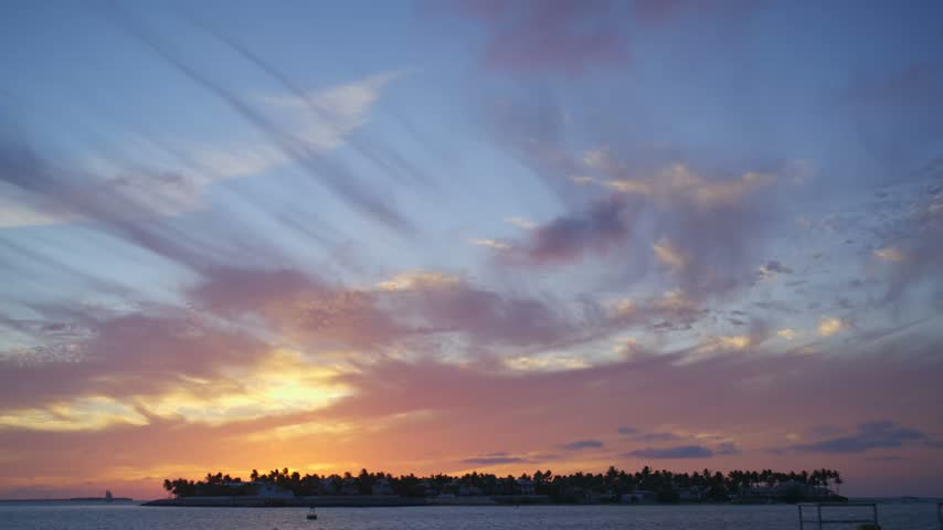 Bright orange sunset sky with clouds over the dark ocean water. Evening cloudscape and natural landscape background.