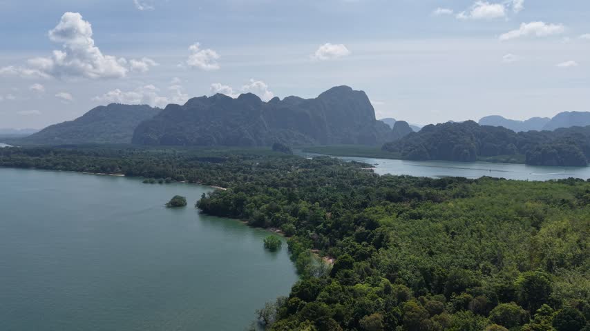 Picturesque tropical landscape with lush island trees, clear sea water, mountain backdrop, and open sky.